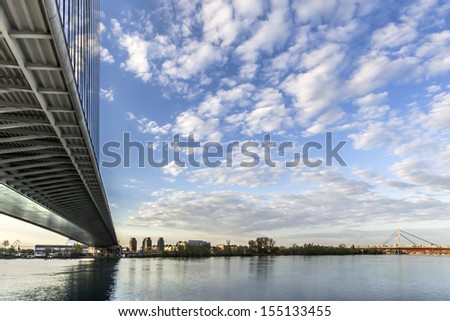 Panoramic photograph of Belgrade and Sava river with the Bridge Over Ada and the New Railroad bridge in the distance, made at dusk, from the lower tip of Ada Ciganlija river isle. 