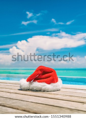 Christmas winter holidays santa hat near swimming pool of Caribbean resort travel vacation destination. Vertical backdrop of paradise vacations.