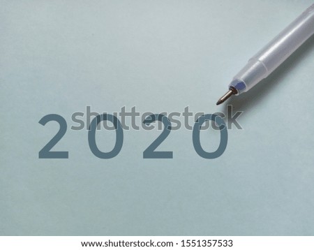Pen placed on light blue paper with number "2020", new year 2020 concept. 