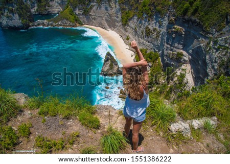 Girl with golden hair, dark glasses and a white T-shirt on the island of Nusa Penida on the background of a paradise beach Diamond beach.