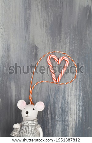Greeting Valentine's day card with a mouse thinking about love on blue background . copy space close up flat lay