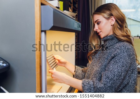 Portrait of smiling female interior designer sitting at office desk. color comparison equipment