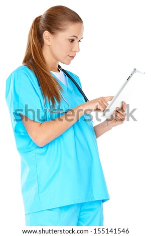 Dedicated young female nurse or doctor in green scrubs standing checking information on a handheld tablet computer  isolated on white