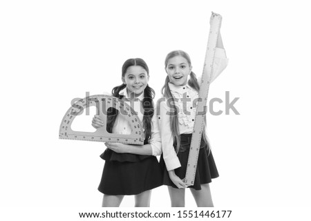 Being ready for lesson. Cute schoolgirls holding protractor and ruler for lesson. Little girls preparing for geometry lesson. Small children with measuring instruments at school lesson.
