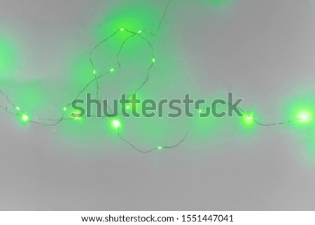 Green color illuminated garland on light gray background