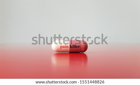 Capsule of analgesic drug or painkiller on background. This medication used for pain relief and analgesia purpose as acetaminophen, opioid or NSAID. Medical technology and pain management concept Royalty-Free Stock Photo #1551448826