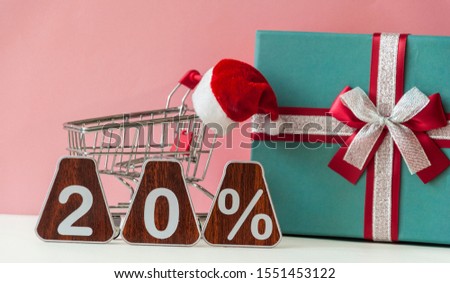 Big sales 20%, twenty percents with Santa hat and christmas gift box over pink background. Christmas sale.
