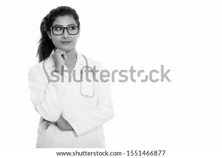 Studio shot of young beautiful Persian woman doctor thinking with eyeglasses