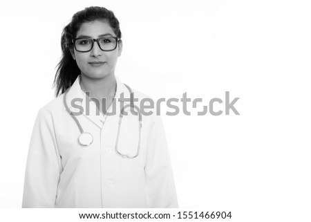 Studio shot of young beautiful Persian woman doctor with eyeglasses