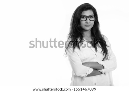 Studio shot of young beautiful Persian woman wearing eyeglasses with arms crossed