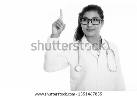 Studio shot of young beautiful Persian woman doctor thinking while pointing finger up
