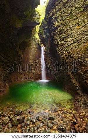 Picturesque view of the rocky amphitheatre with a green pool and a white beam of water. 15-metre-high Kozjak Waterfall (Slap Kozjak). Protected natural treasure. National Park of Triglav, Soca valley. Royalty-Free Stock Photo #1551494879