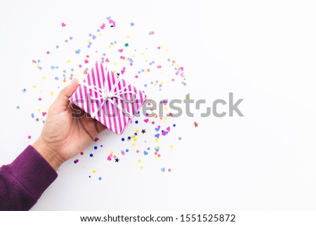 Celebration party and anniversary concepts ideas with young person hand giving gift box decoration with colorful confetti,paper art on white color background.copy space