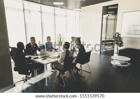 Silhouettes of people sitting at the table. A team of young businessmen working and communicating together in an office. Corporate businessteam and manager in a meeting Royalty-Free Stock Photo #1551539570