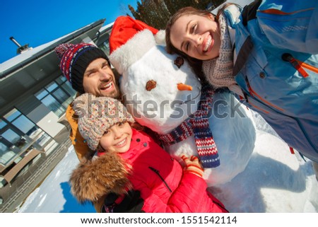 Family on a winter vacation spending time together outdoors standing near the house taking selfie picture with snowman looking camera smiling happy close-up