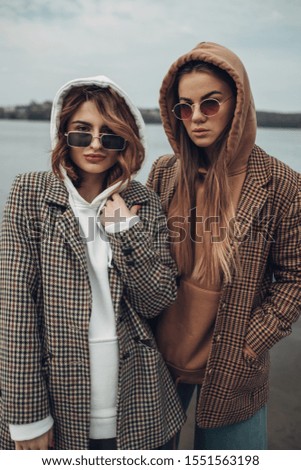 Portrait of Two Fashion Girls, Best Friends Outdoors, Wearing Stylish Jacket, Walking Near the Lake