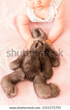 Little arms with furry grey rabbit
