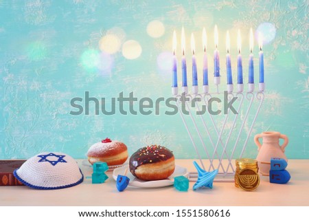 religion image of jewish holiday Hanukkah with menorah (traditional candelabra), spinning top and doughnut over pastel blue background