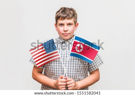 teen boy holds the flags of the United States and North Korea