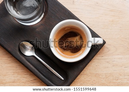 black coffee in a cup and a transparent glass with water on a wooden background. glare in the sun. Espresso