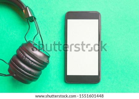 Headphones and smartphone on colorful background. Flat lay concept: headphones and telephone on green pastel backgrounds.