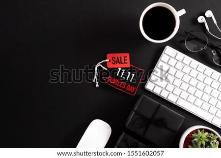 Online shopping of China, 11.11 singles day sale concept. Red paper tag with keyboard mouse coffee cup, gift box and earphone on black background with copy space for text 11.11 singles day sale.