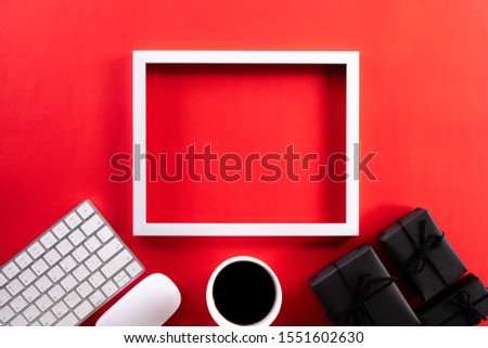 White picture frame with keyboard mouse coffee cup, gift box and Christmas tree decoration on red background. Online Shopping concept and black Friday composition.