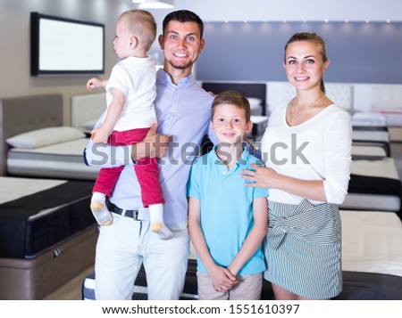 Portrait of happy family visiting furniture salon in search of new mattress for purchase