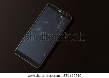 Broken smartphone screen with cracks close up on a black background
