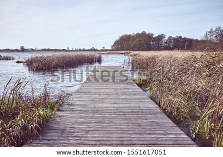Retro toned picture of a wooden pier by lake in Autumn.
