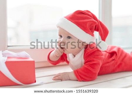 Beautiful little baby celebrates Christmas. New Year's holidays. Baby in a Christmas costume and in santa hat