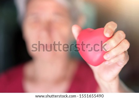 Soft focus at hand of elderly taking care and holding red heart ball in her hand. Concept love and take care family , Support senior people. Inheritance and bequest. Health Claims and Life insurance. Royalty-Free Stock Photo #1551655490