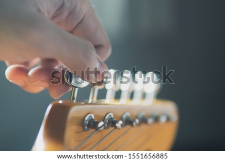 Tuning guitar string by adjusting tuning machines Royalty-Free Stock Photo #1551656885