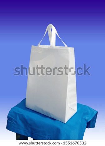 White Grocery Non Woven Eco Friendly Bag on blue table for Shopping, blue background 