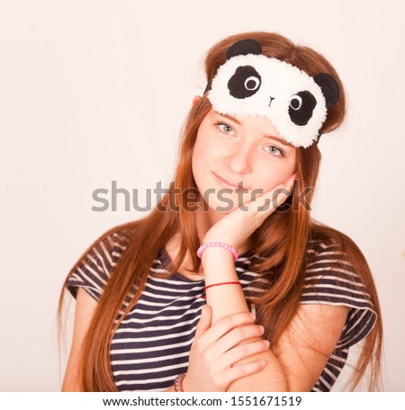 Smiling happy young redhead woman wearing striped sleeping eye mask feeling fresh after good night healthy sleep in the morning isolated