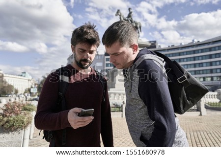 Two young tourists looking their mobiles in Sofia. Bulgaria