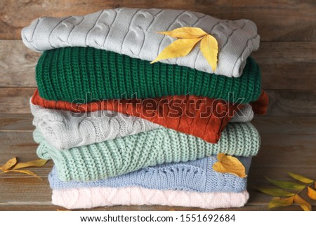 Stack of sweaters on wooden background. Autumn clothes
