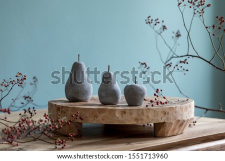 Stylish autumn composition of home decor on living room with wooden fruit tray, cement fruits and autumn flwoers. Eucalyptus color concpet. Template. Modern decoration. Close up. 