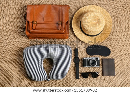 Flat lay composition with travel pillow and tourist stuff on wicker rug