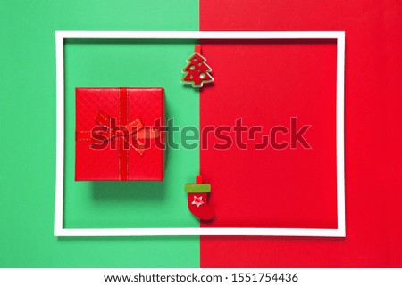Christmas composition with present box and decorative fir tree on red and green background with white frame. Winter holiday concept. Top view. Flat lay