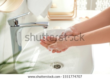 Young woman washing hands with soap over sink in bathroom, closeup Royalty-Free Stock Photo #1551774707