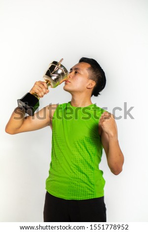 Happy young athlete celebrating a victory with his trophy