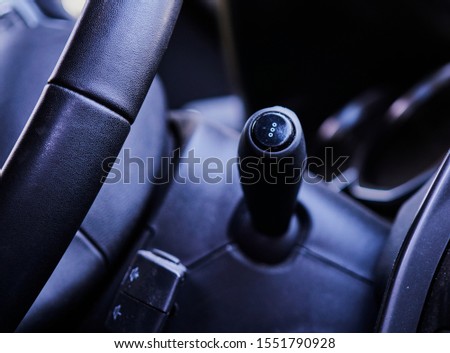 View of the turn signal lever and a part of the steering wheel in the front interior of a car