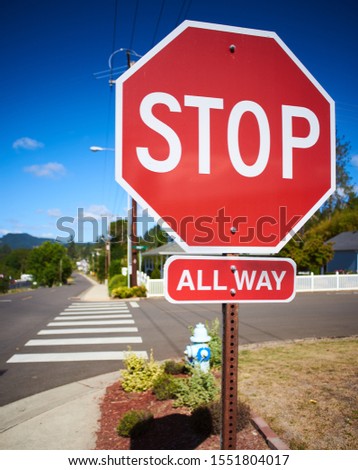 Octagonal stop sign at the all-way stop. Typical for road intersection in an American city.