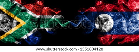 South Africa vs Laos smoky mystic flags placed side by side. Thick colored silky abstract smoke flags concept