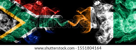 South Africa vs Ivory Coast smoky mystic flags placed side by side. Thick colored silky abstract smoke flags concept