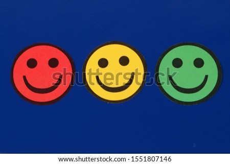 three cut out traffic lights colored smileys lie side by side on a blue background in the studio