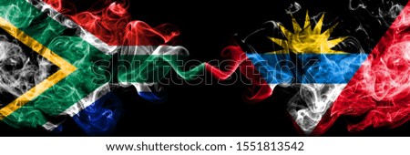 South Africa vs Antigua and Barbuda smoky mystic flags placed side by side. Thick colored silky abstract smoke flags concept