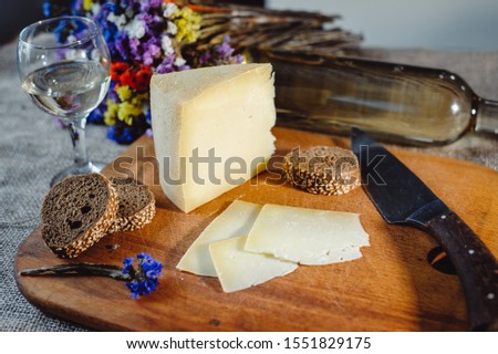 A piece of ripe Comte or Gruyere de Comte, French AOC cheese made from cow's milk, sliced on a wooden board. Cheese composition. Beaufort