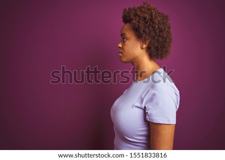 Young beautiful african american woman with afro hair over isolated purple background looking to side, relax profile pose with natural face with confident smile.